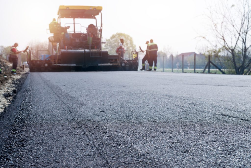 Workers placing new coating of asphalt on the road 601