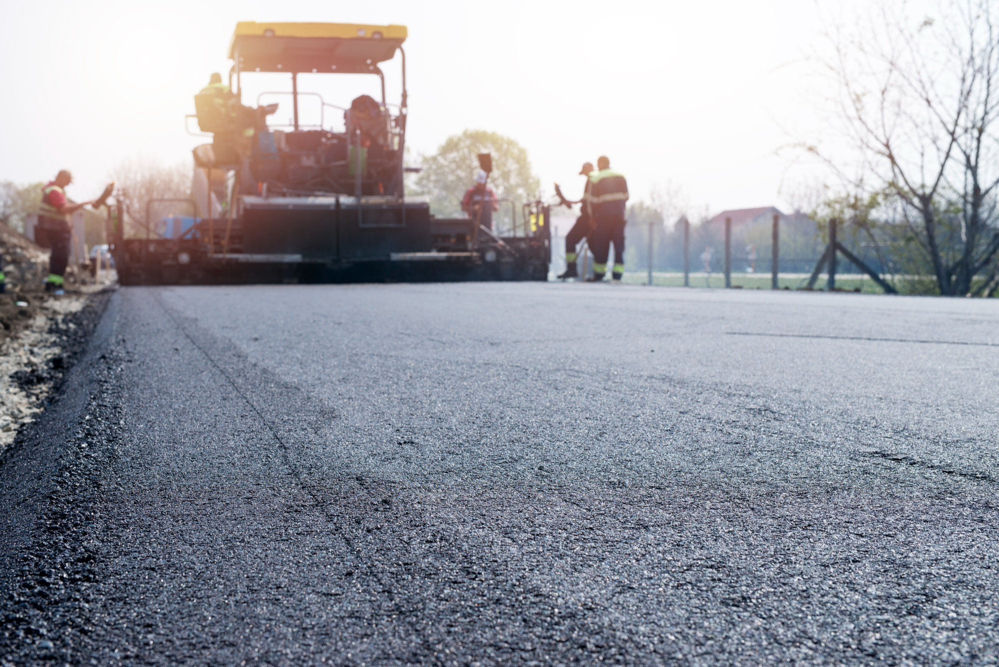 Workers placing new coating of asphalt on the road 601