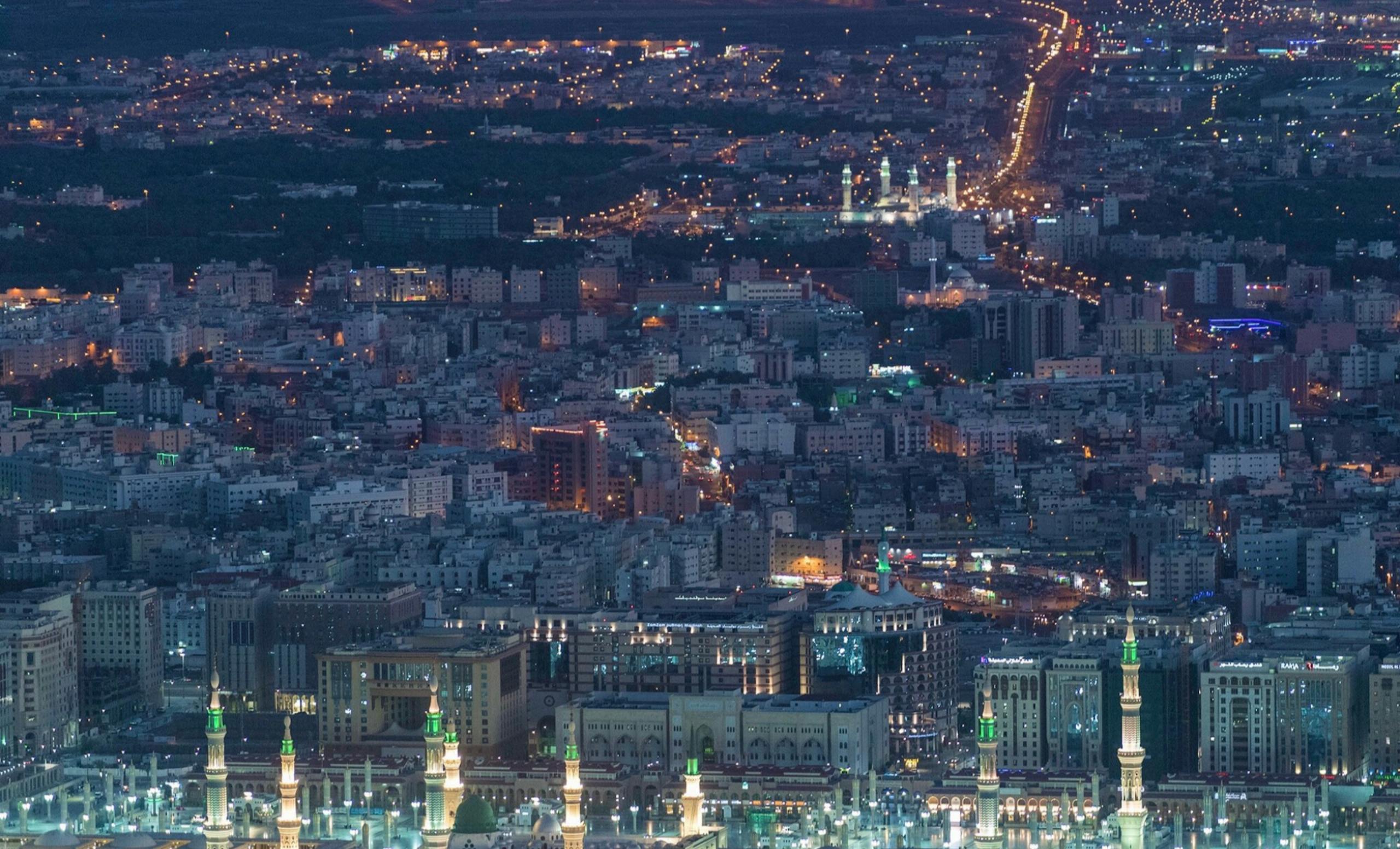 Stunning aerial night view of Medina, Saudi Arabia, showcasing urban lights and architecture.